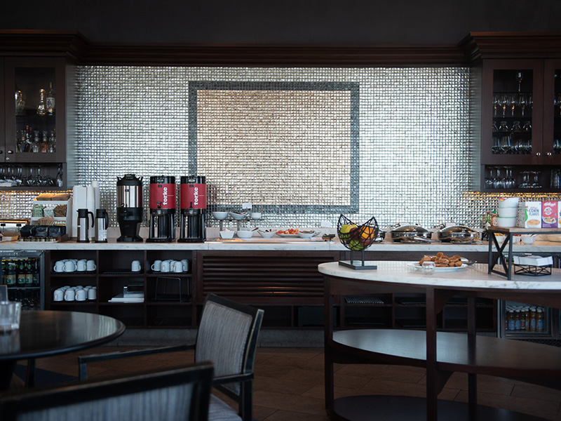 Breakfast buffet area with coffee dispensers, pastries, cereals, and fresh fruit.