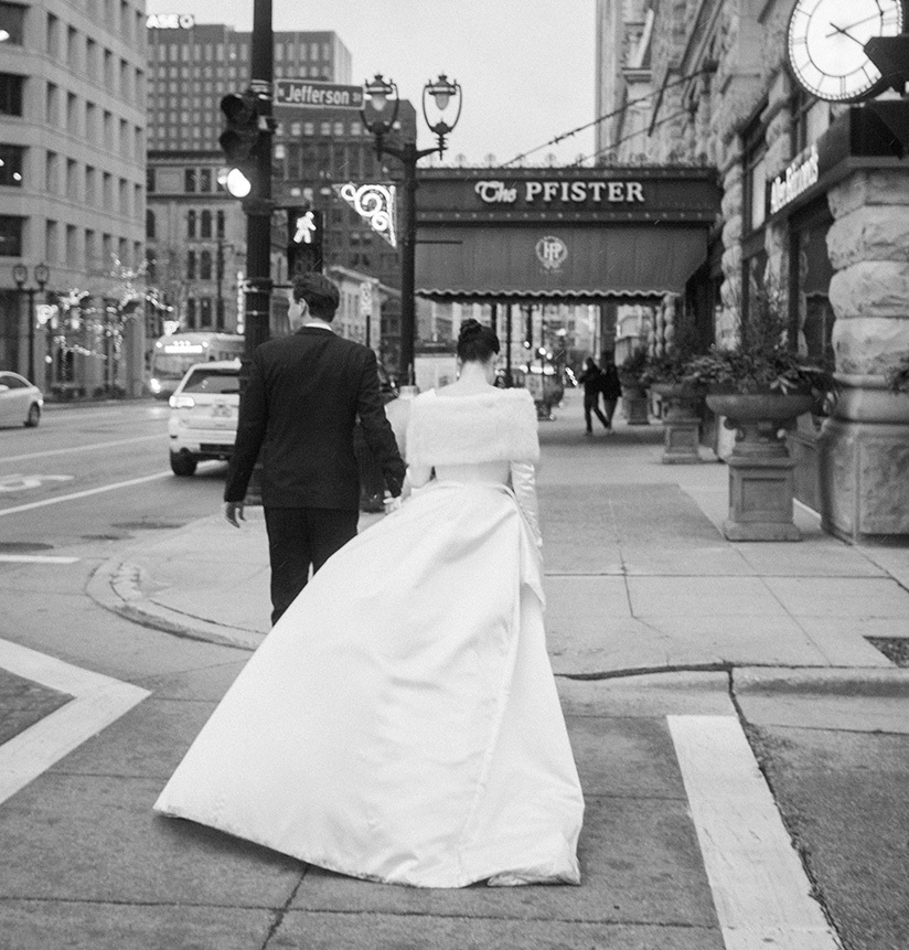Bride and groom walking by Pfister hotel signage exterior