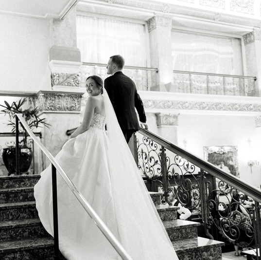 Bride and groom ascending large staircase